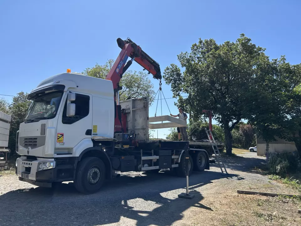 Camion-grue de la marbrerie déployant son bras pour décharger une dalle de caveau