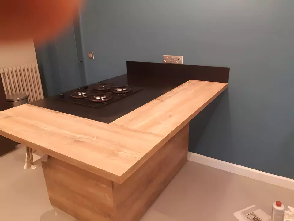 Plan de travail en pierre noire mate avec crédence assortie, associé à un retour en bois clair