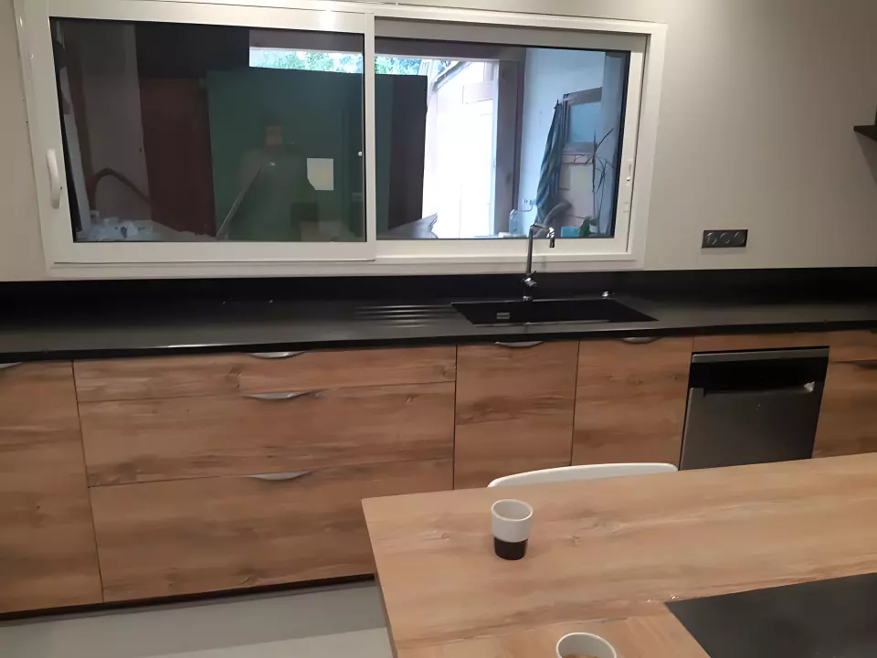Plan de travail en pierre noire avec évier intégré sous plan, le long d'une cuisine en bois