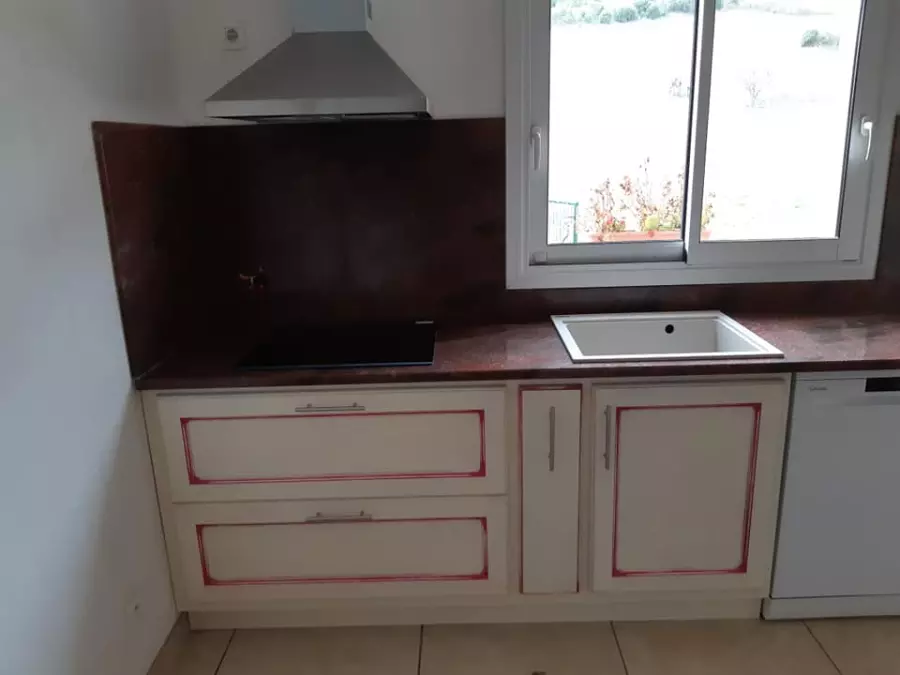 Plan de travail et crédence en pierre rouge sombre sur un meuble de cuisine blanc à filets rouges