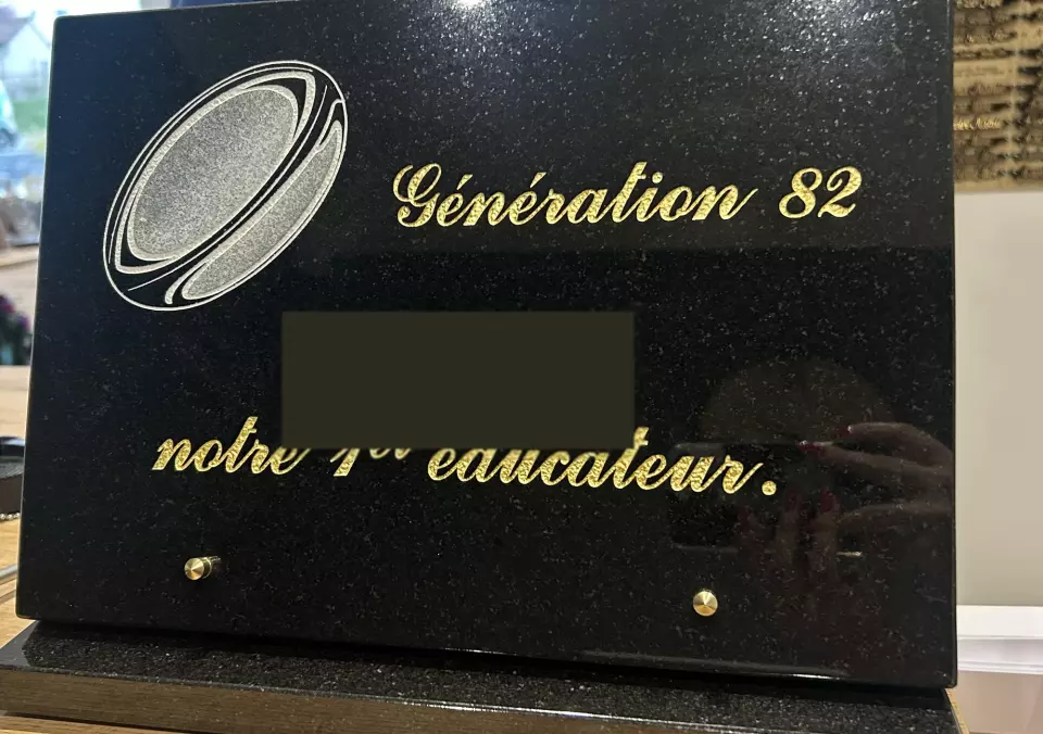 Plaque en granit noir gravée d'un ballon de rugby, dédicace dorée à un éducateur de club