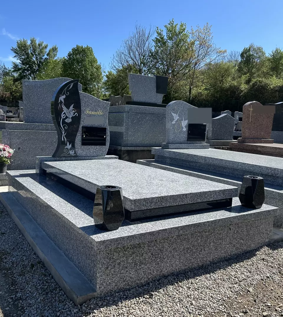 Le même monument vu de trois quarts : tombale en granit gris sur soubassement, stèle à vague noire gravée